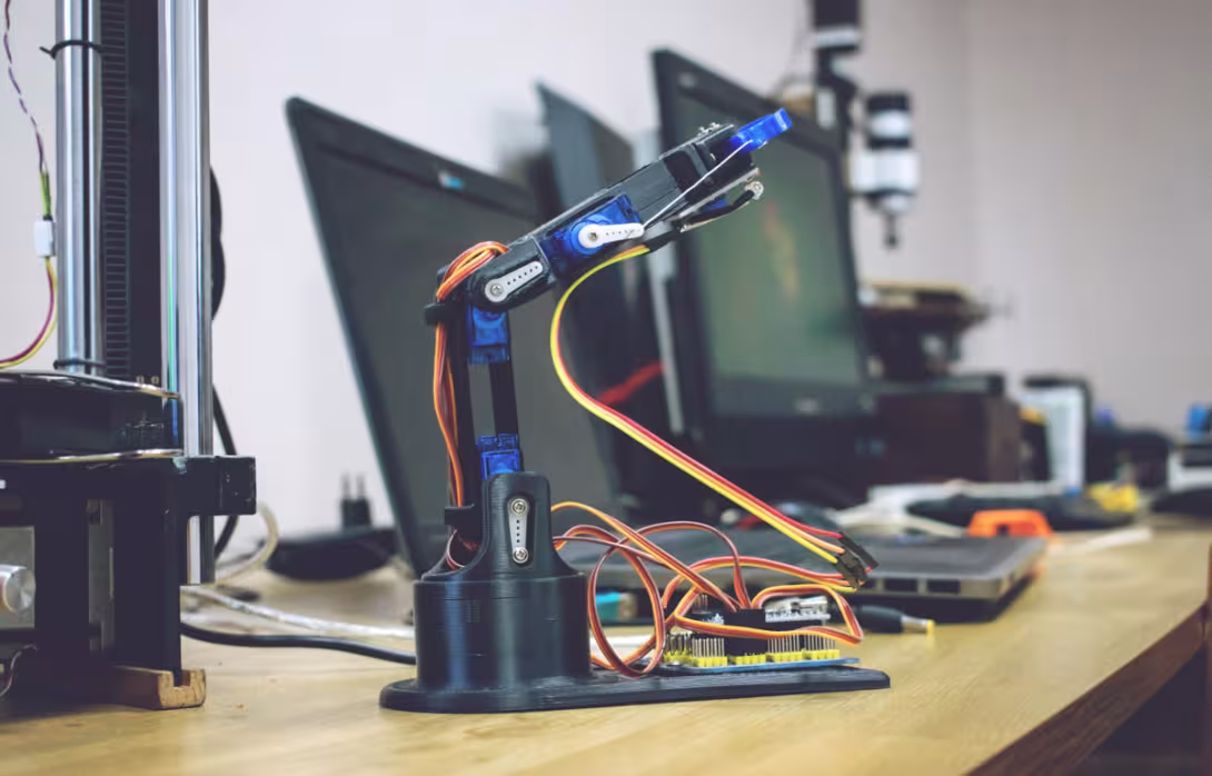A 3D-printed robotic arm prototype sits on a workstation, wired for testing and programming. It reflects the creativity and innovation driving modern robotics.